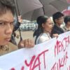 Tiga pemuda melakukan aksi jahit mulut di Bundaran Tugu Adipura Bandar Lampung saat kunjungan Presiden Prabowo Subianto sebagai bentuk kritik terhadap kondisi demokrasi dan ekonomi.