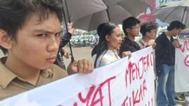 Tiga pemuda melakukan aksi jahit mulut di Bundaran Tugu Adipura Bandar Lampung saat kunjungan Presiden Prabowo Subianto sebagai bentuk kritik terhadap kondisi demokrasi dan ekonomi.