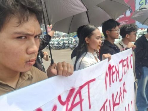 Tiga pemuda melakukan aksi jahit mulut di Bundaran Tugu Adipura Bandar Lampung saat kunjungan Presiden Prabowo Subianto sebagai bentuk kritik terhadap kondisi demokrasi dan ekonomi.